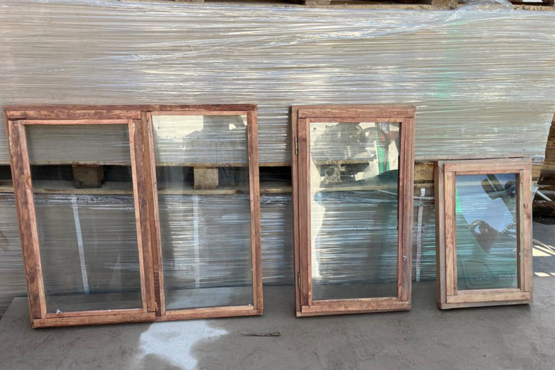 Four wooden mirrors with glass panels on a concrete floor.