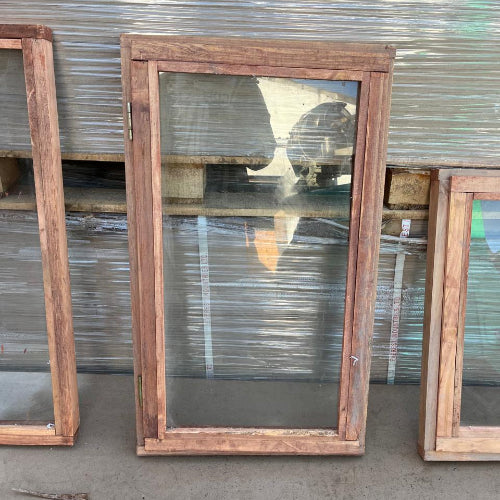 Wooden frames with glass panels against a corrugated metal background
